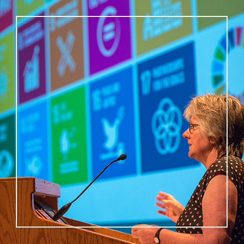 speaker presenting in front of screen with colorful logos