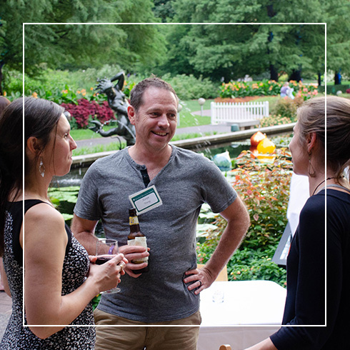 young people speaking while holding drinks outside