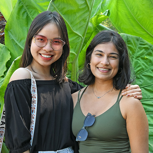 Couple posing in front of large tropical leaves